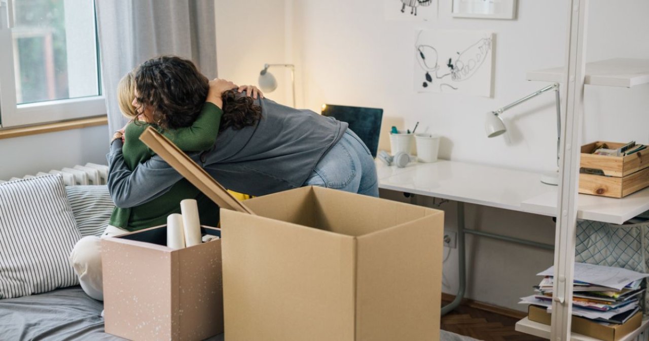 Female student and parent in dorm room surrounded by moving boxes